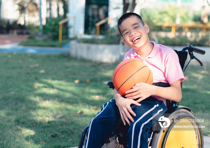 Disabled child on wheelchair is playing basketball on the lawn in front of the house like other people, Lifestyle of special child,Life in the education age of children, Happy disability kid concept.