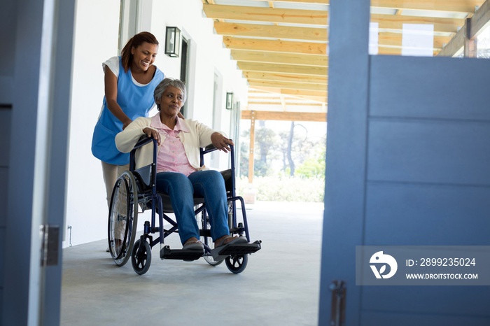 Female doctor pushing happy senior patient in wheelchair