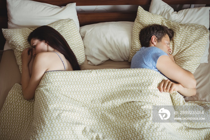 Couple sleeping back to back and ignoring each other on bed