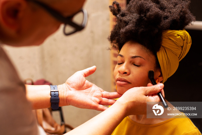 Portrait of a  make up artist applying makeup to a young woman with a professional brush on a photo shoot set