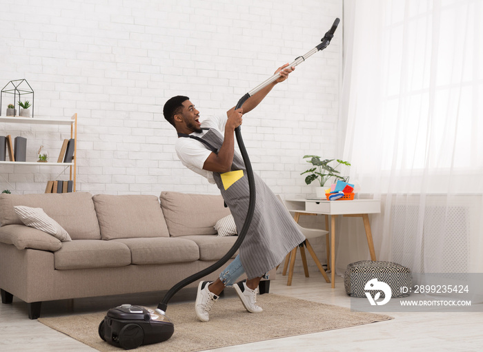 Young man cleaning house with vacuum cleaner