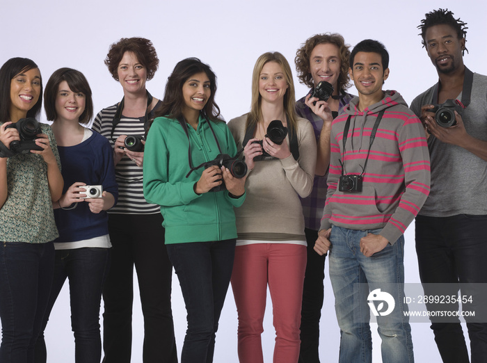 Group portrait of multiethnic young people holding cameras in studio