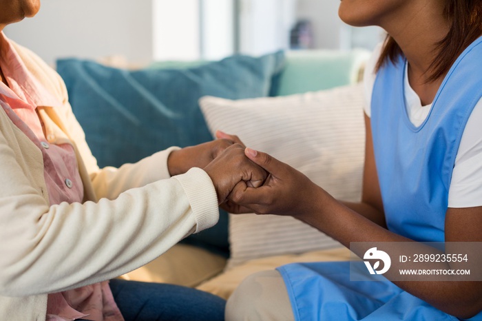 Female doctor comforting senior woman in living room