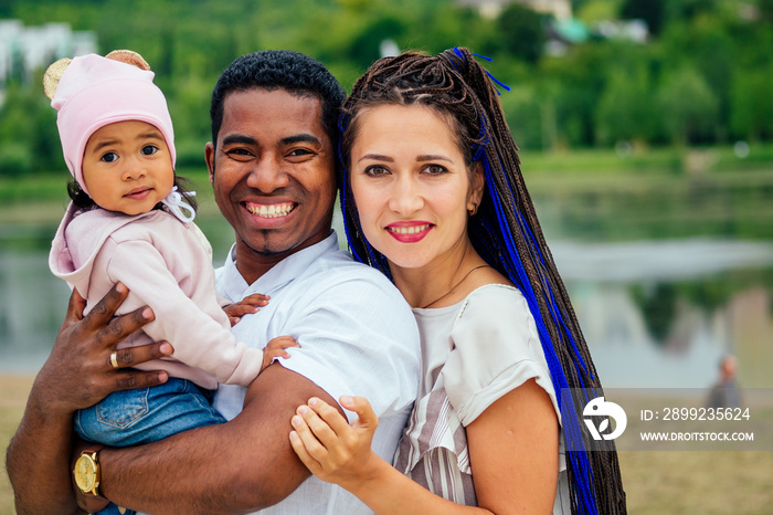 transnational interracial mother and father walking with their mixed race baby girl in autumn park