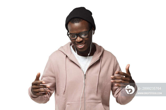 Young happy black man smiling, listening music via headphones, dancing with closed eyes