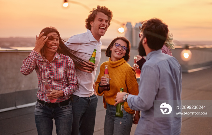 Cheerful friends with drinks enjoying party on rooftop