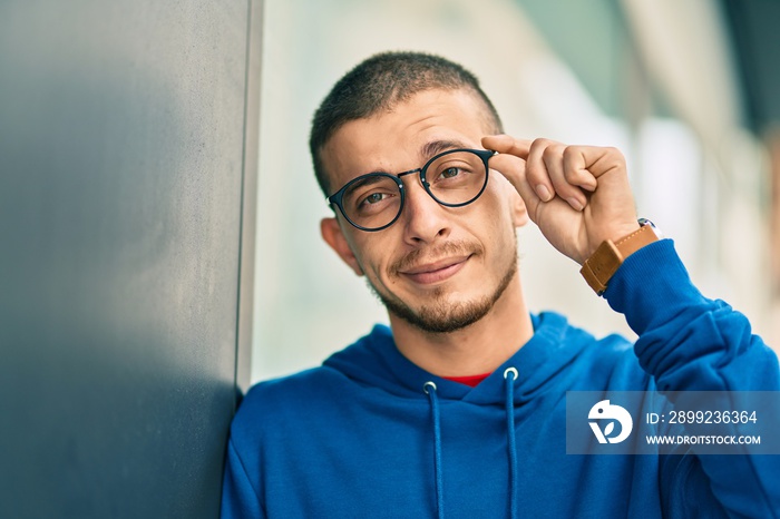 Young hispanic man smiling happy standing at the city.