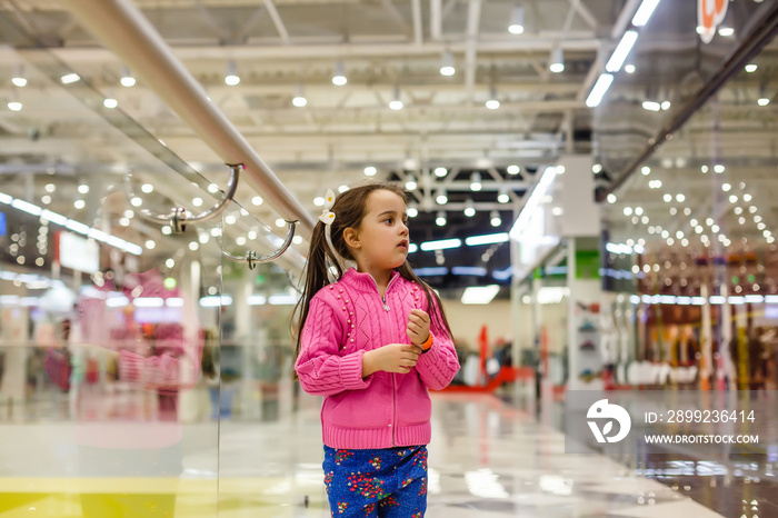 Little girl alone in shopping mall center, looking for her mother. The child was lost in the big store.