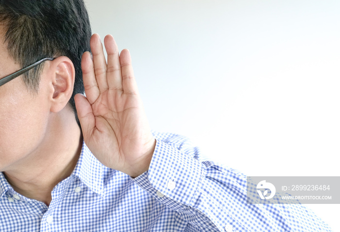 Businessman holds his hand near his ear, a listening gesture or concept