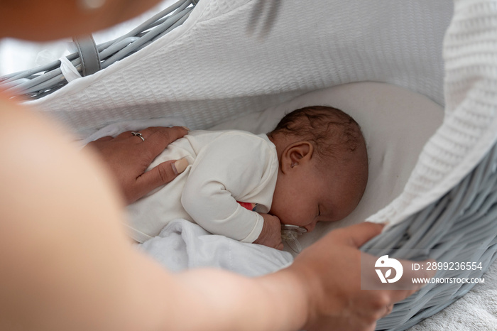 Mother putting to sleep newborn baby girl in crib