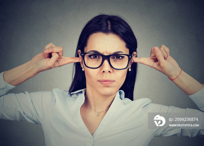 Angry woman plugging her ears with fingers