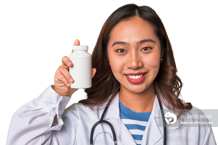 A young Chinese doctor holding a pill container with a smile, promoting health and wellness through medication and care.