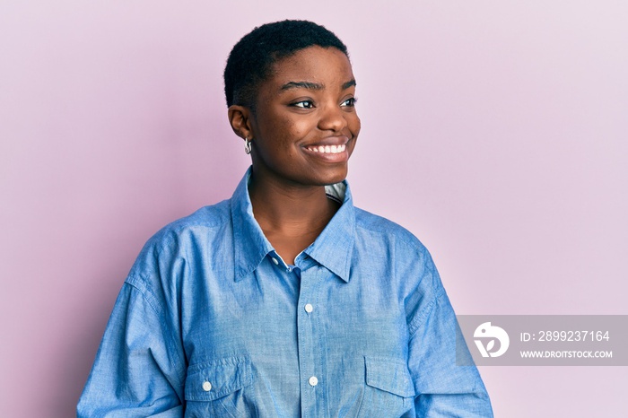 Young african american woman wearing casual clothes looking away to side with smile on face, natural expression. laughing confident.