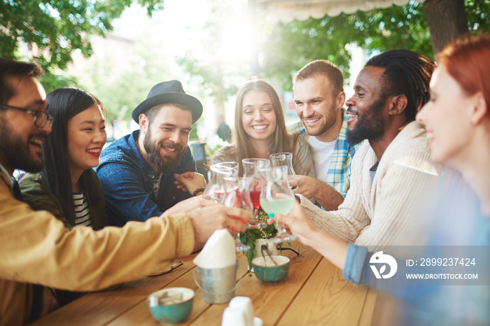 Group of friendly hipsters with drinks enjoying time in cafe