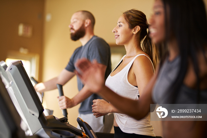 three people using treadmills in gym together