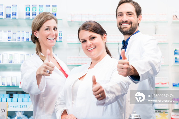 Pharmacists in pharmacy showing thumbs up and smiling