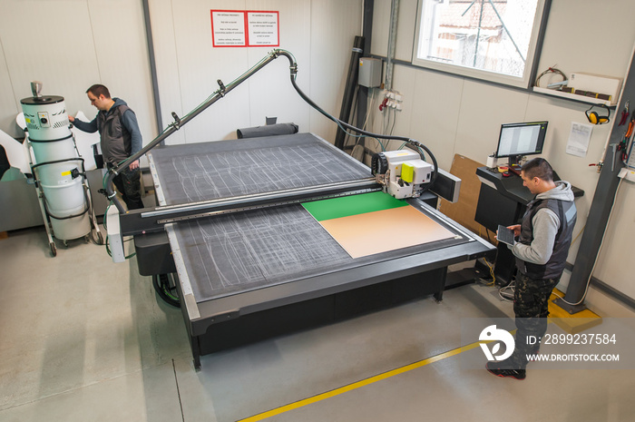 Two technicians works on CNC computer numerical control cutting machine