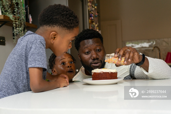 Father and children (2-3, 6-7) preparing birthday cake