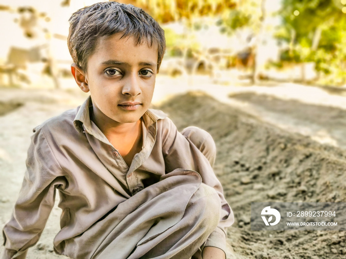 closeup of a poor staring hungry orphan boy in a refugee camp with sad expression on his face and his face and clothes are dirty and his eyes are full of pain