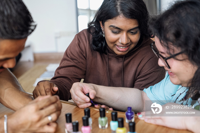 Three friends painting their nails together at home