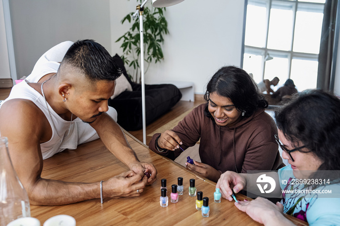 Three friends painting their nails together at home