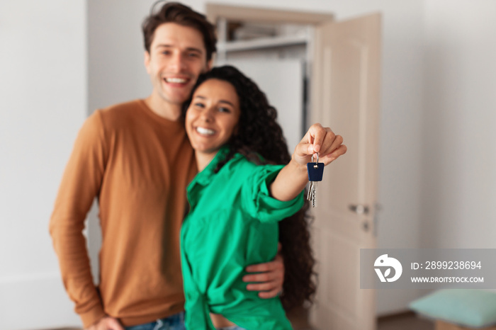 Happy man and woman posing with keys on moving day