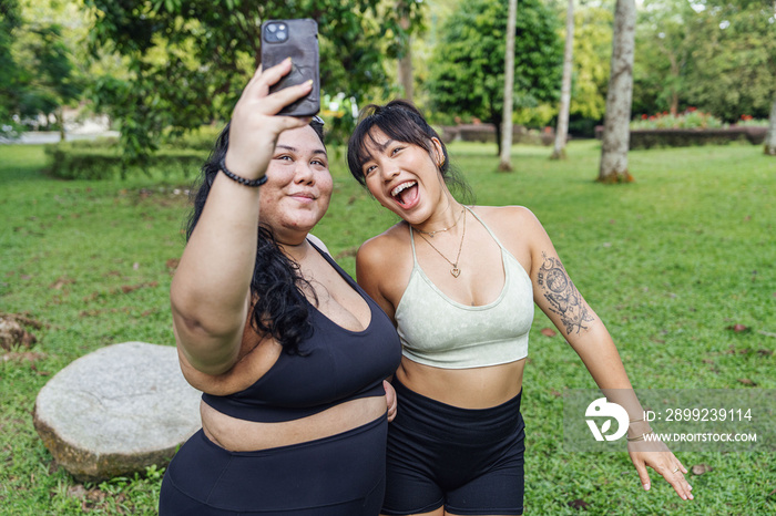 Friends taking photos of each other in the park after a workout