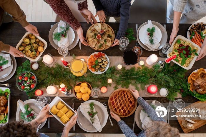 Top view of hands of family members holding plates with homemade food