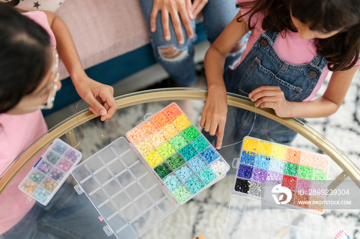 Sisters playing with beads in living room