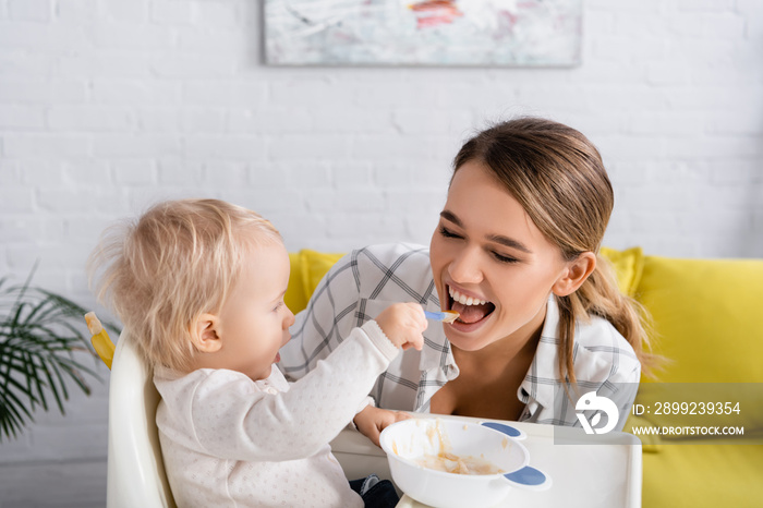 little boy feeding happy mother while sitting on kids chair