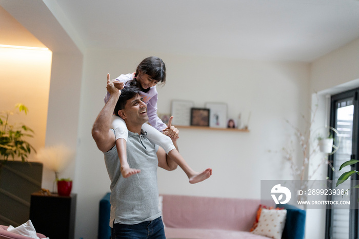 Father carrying daughter on shoulders at home