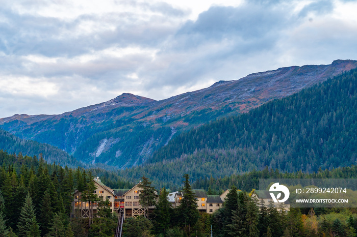 Traditional charming brown cabin lodge duplex homes nestled in the mountains among pine trees with gable roofing and glass windows above street level in Alaska.