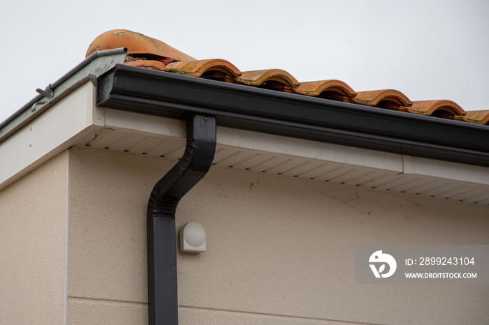 metal black gutter on home roof covered with ceramic tiles Close up