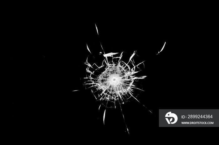 Texture of broken glass. Hole from a ball on a black background.