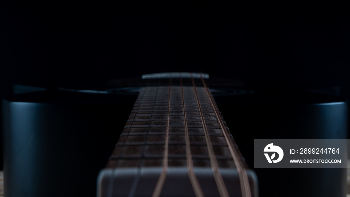 hand touching the strings of the guitar. black guitar fretboard. acoustic guitar in the dark