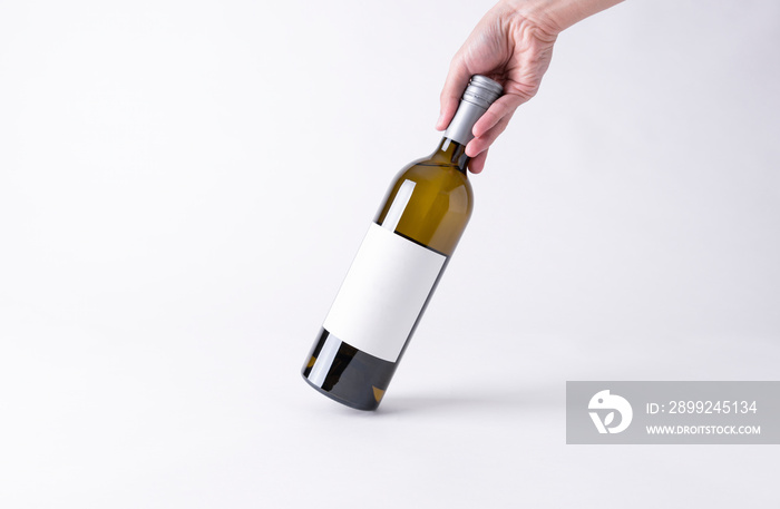 Hand holding a wine bottle for mock-up. Blank Label on a gray background.