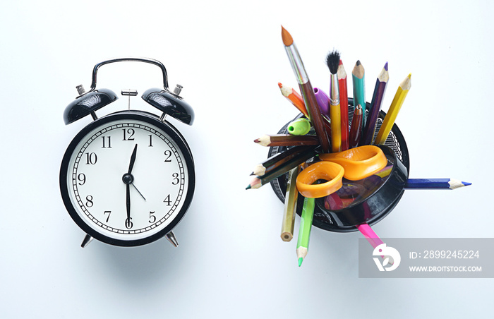 Alarm Clock and School Stationary in Basket on White Background