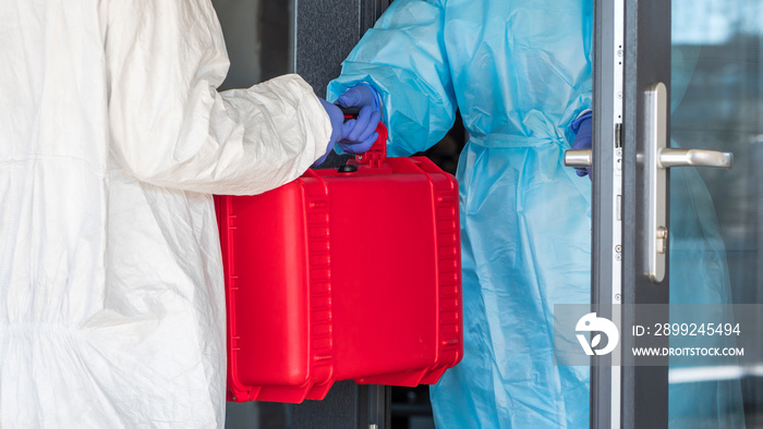 A courier in a protective suit hands the doctor a red case with valuable medicines