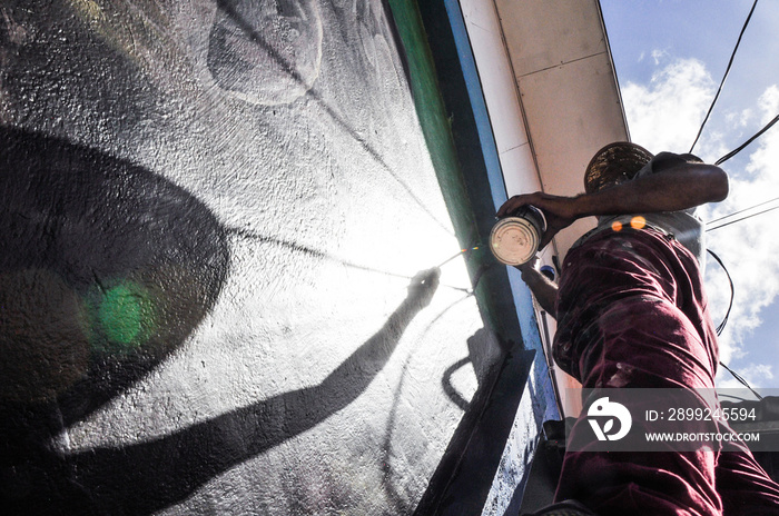 Silhoutte of a paintor doing a mural