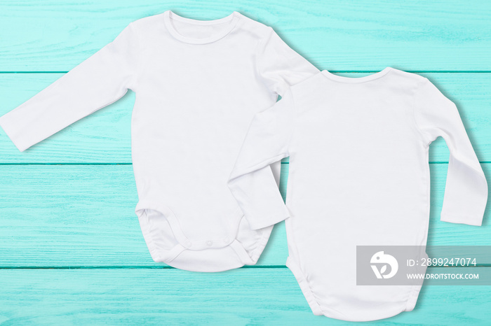 White baby mock up jumpsuit on blue wooden background. Baby bodysuit mockup and template blank copy space. Top view. One-piece newborn shirt clothes mock-up. Front Back rompers view