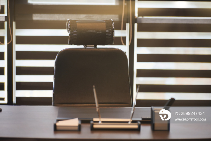 Business office workplace. Sunlight at work place for chief, boss or other employees. Table and comfortable chair. Light through the half open blinds