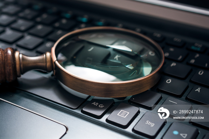 Vintage Magnifying Glass On A Black Notebook Keyboard - SEO Concept