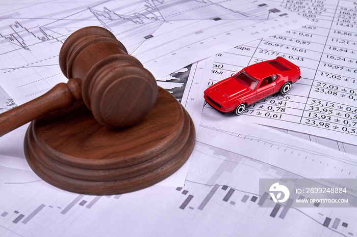 Car credit debt concept. Wooden judgle gavel and miniature toy red car on a pile of papers.