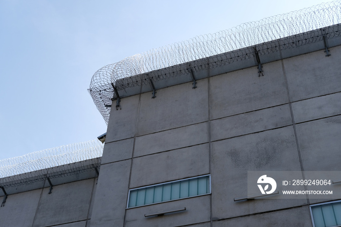 many rows of barbedwire, high concrete fence, barbed wire fence on top, building for execution of punishments for criminals, concept prison, security zone, symbol of bondage, hopelessness of captivity