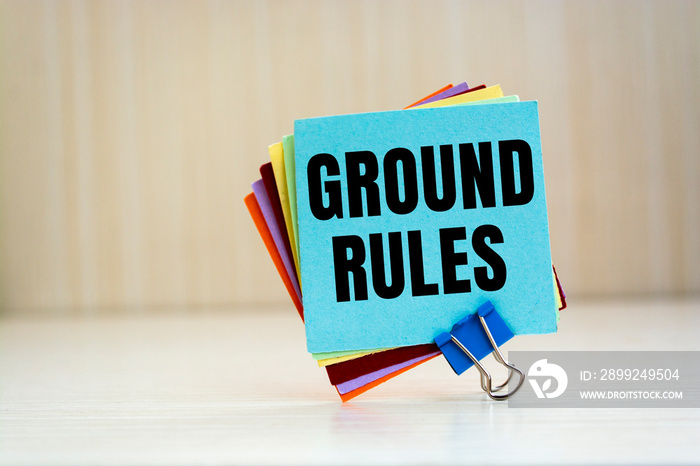 Notebook with text GROUND RULES on office table with office supplies.