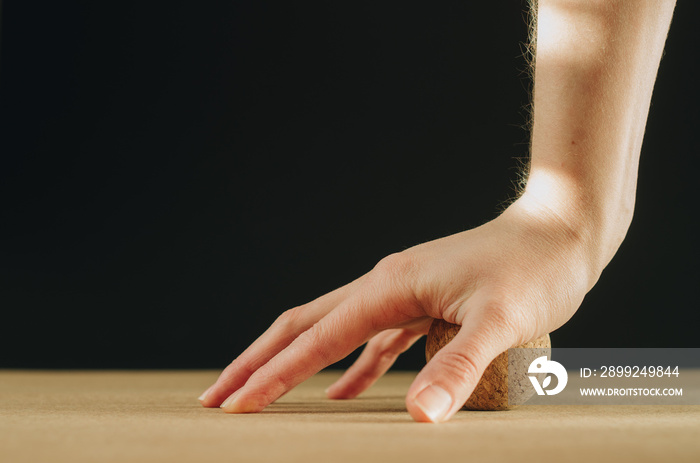 Side view of person doing palmar fascia release with a small cork ball on a black background with golden light, with copy space. Concept: self care practices at  home