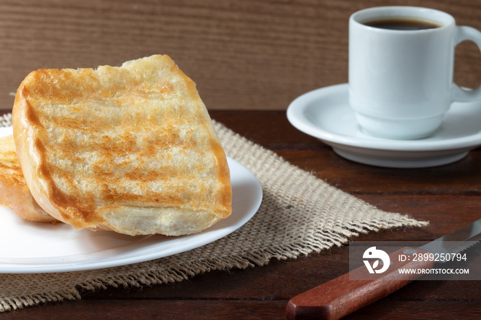 Toasted bread with butter and black coffee, selective focus.