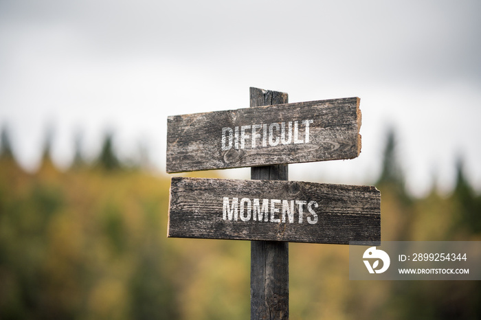 vintage and rustic wooden signpost with the weathered text quote difficult moments, outdoors in nature. blurred out forest fall colors in the background.