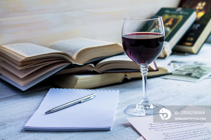 Glass of red wine and a book on a white wooden background