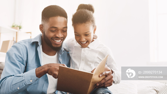 Weekend together. Loving father reading book to his daughter